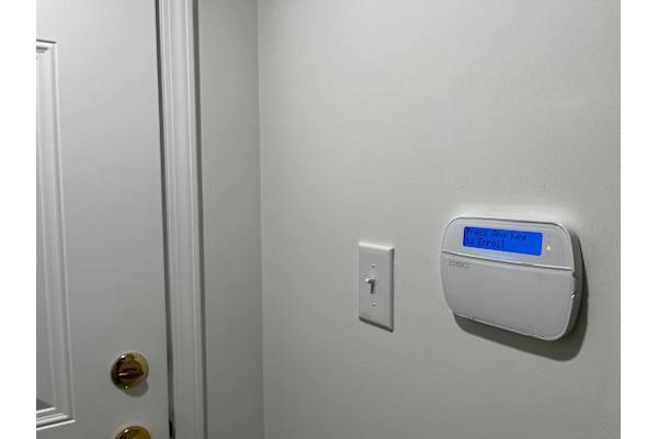A white door with a white light switch and a white wall.